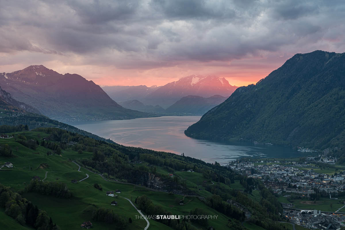 Abendstimmung über dem Talkessel von Schwyz mit Vierwaldstättersee und umliegenden Bergen unter dramatischem Himmel.