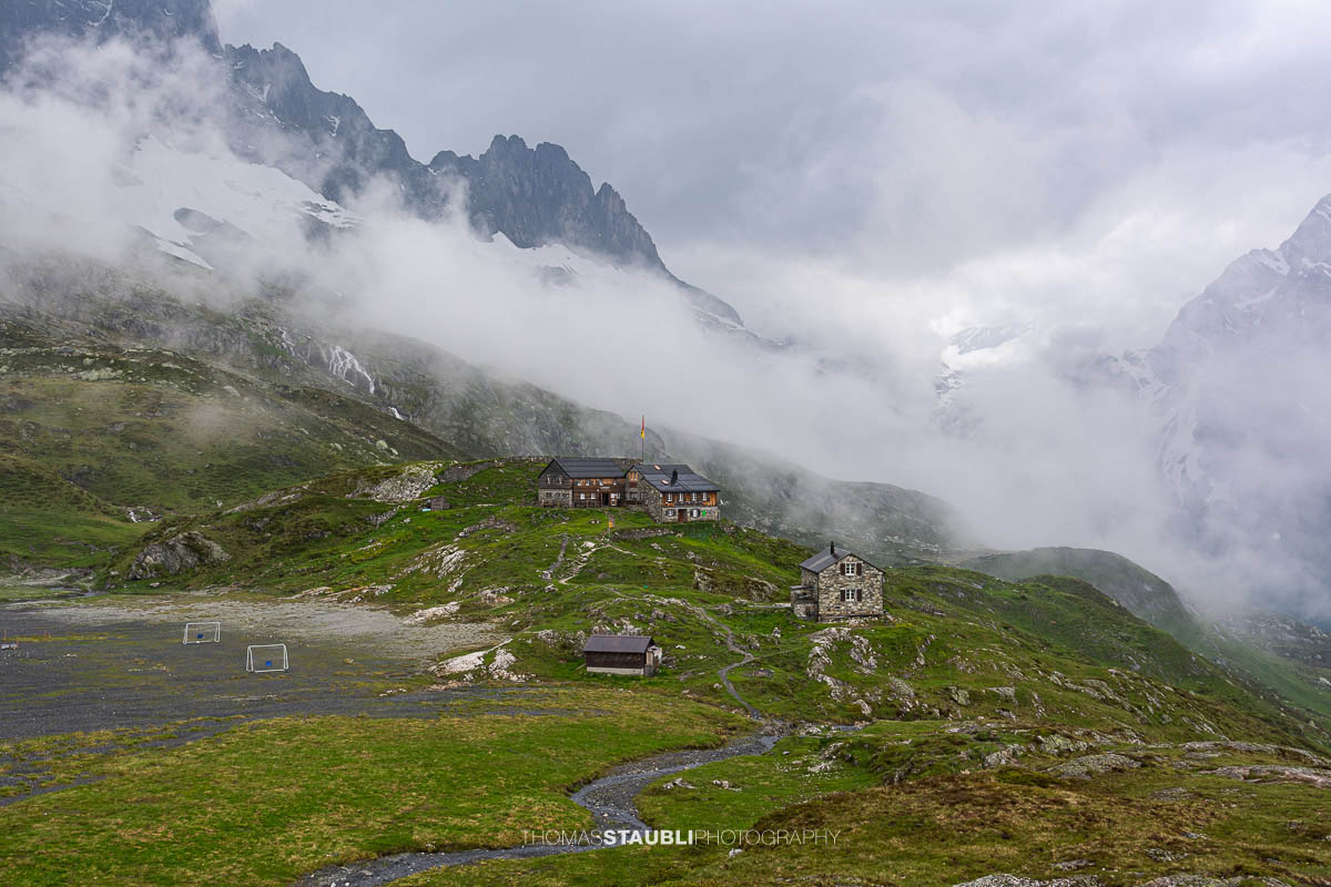 Die Windgällenhütte im Maderanertal, umgeben von Nebelschwaden und den Gipfeln der Urner Alpen.
