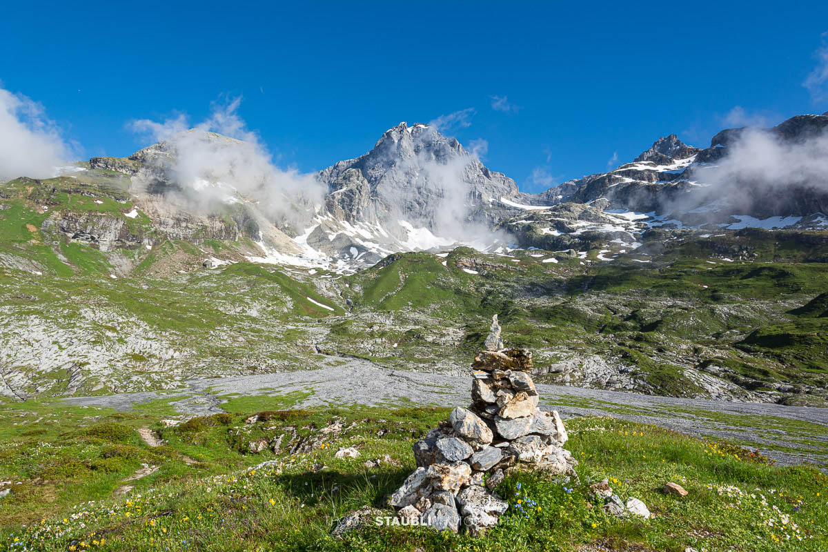 Blick zum Gross Windgällen im Maderanertal mit alpinen Wiesen, Schmelzwasserbach und aufziehenden Nebelschwaden.