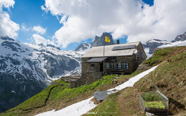 Hüfihütte oberhalb des Maderanertals vor einer beeindruckenden Kulisse aus Gletschern, Felsgipfeln und Schneefeldern.