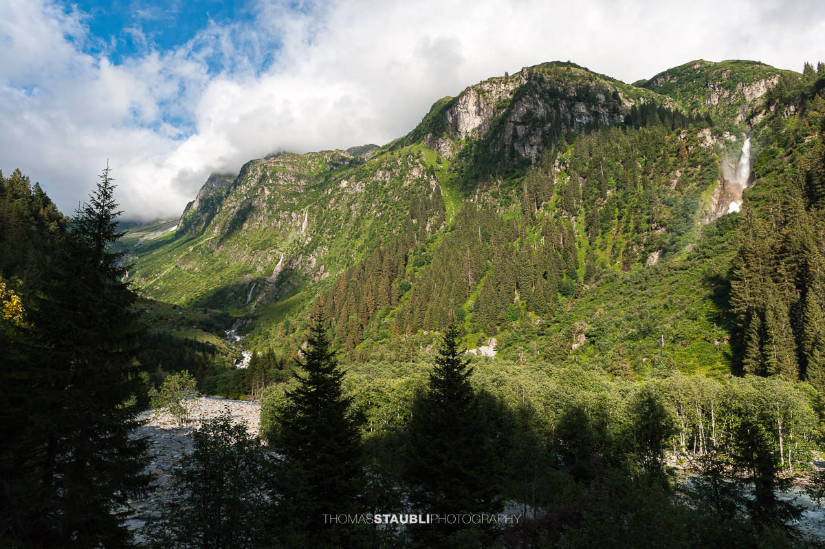 Blick auf den Stäuber Wasserfall im Maderanertal mit bewaldeten Berghängen und dem Chärstelenbach.