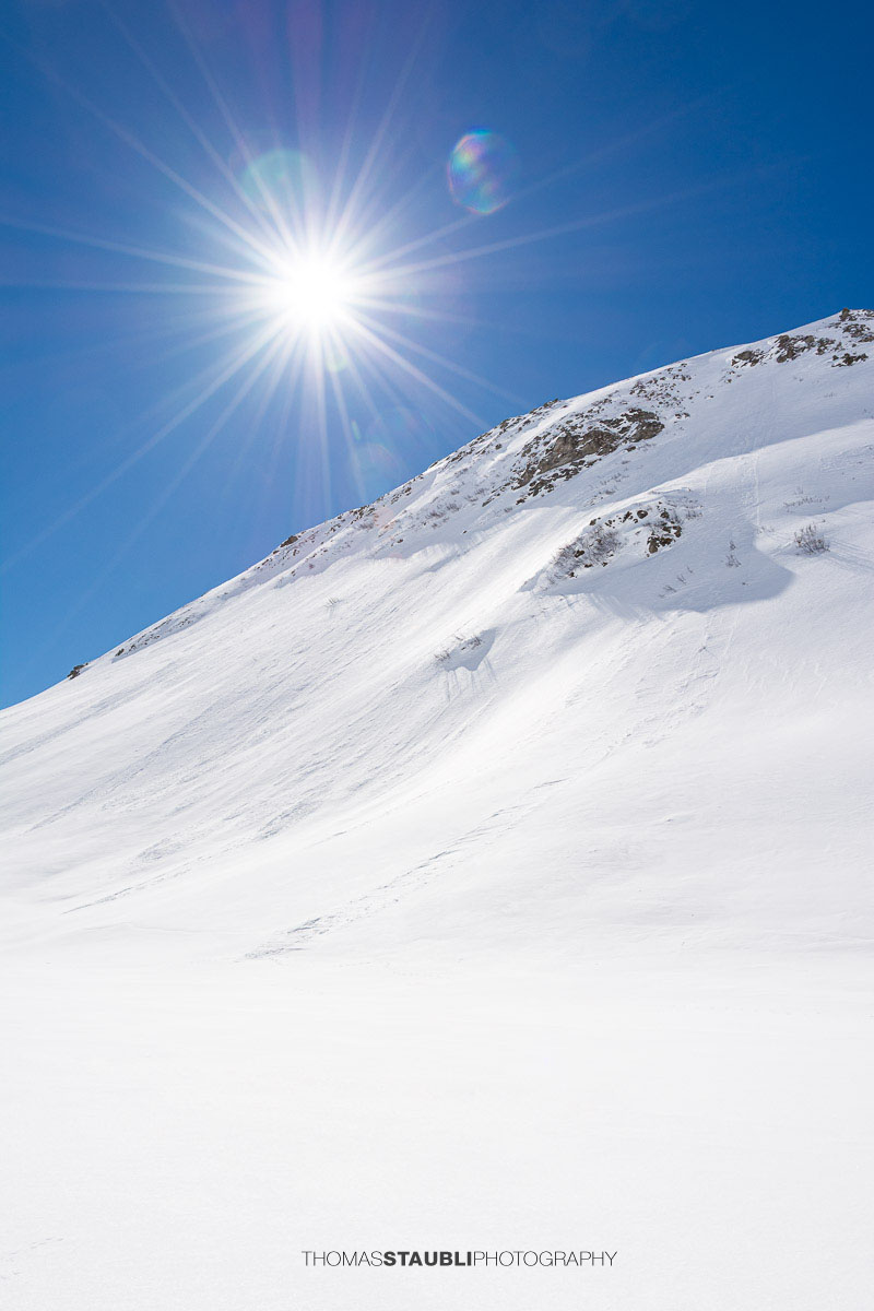 Sonne und blauer Himmel über der verschneiten Berglandschaft auf dem Oberalppass
