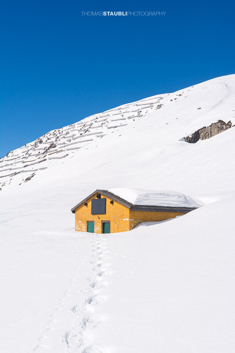 tief verschneite Alphütte auf dem Oberalppass
