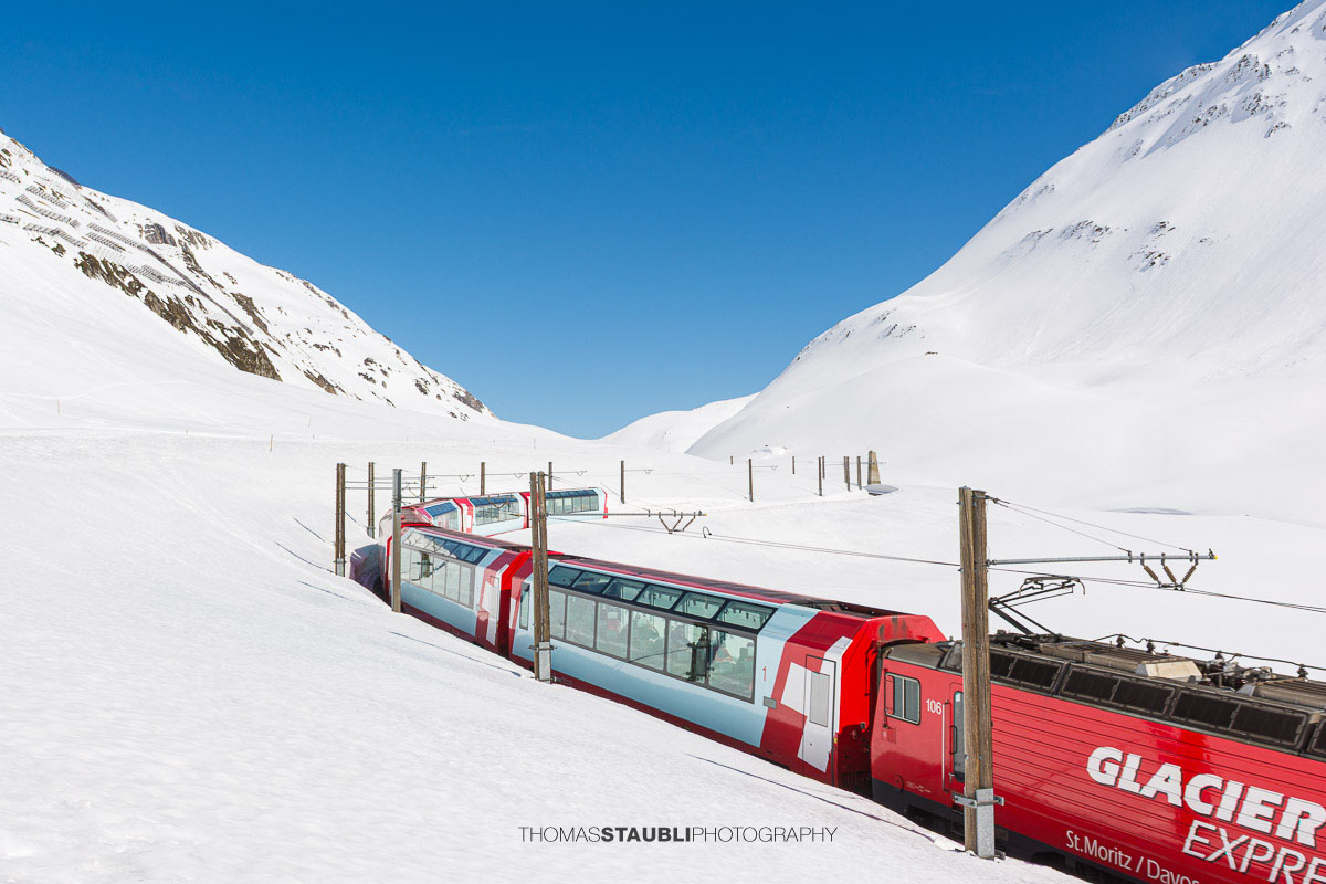 Glacier Express fährt durch die verschneite Landschaft am Oberalppass.