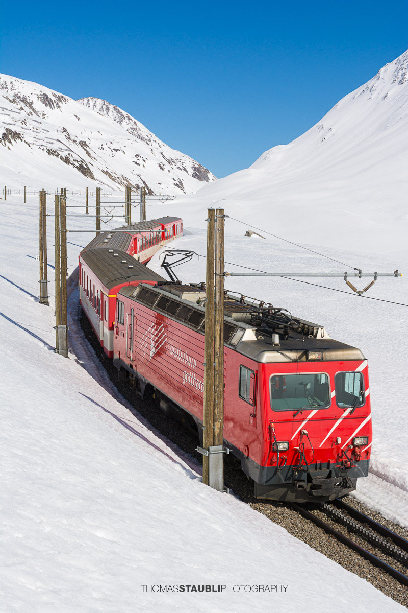 Matterhorn Gotthard Bahn fährt durch die verschneite Landschaft am Oberalppass.