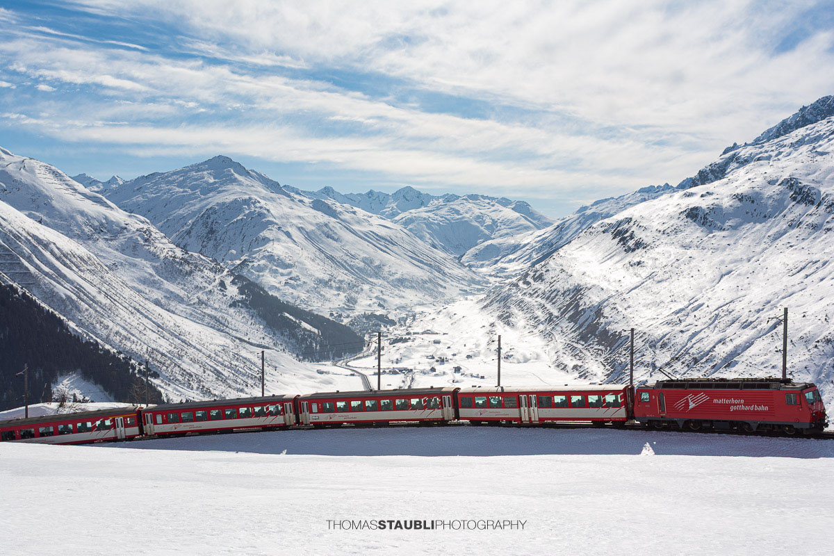 Matterhorn Gotthard Bahn am Oberalppass mit Blick über das verschneite Urserental.