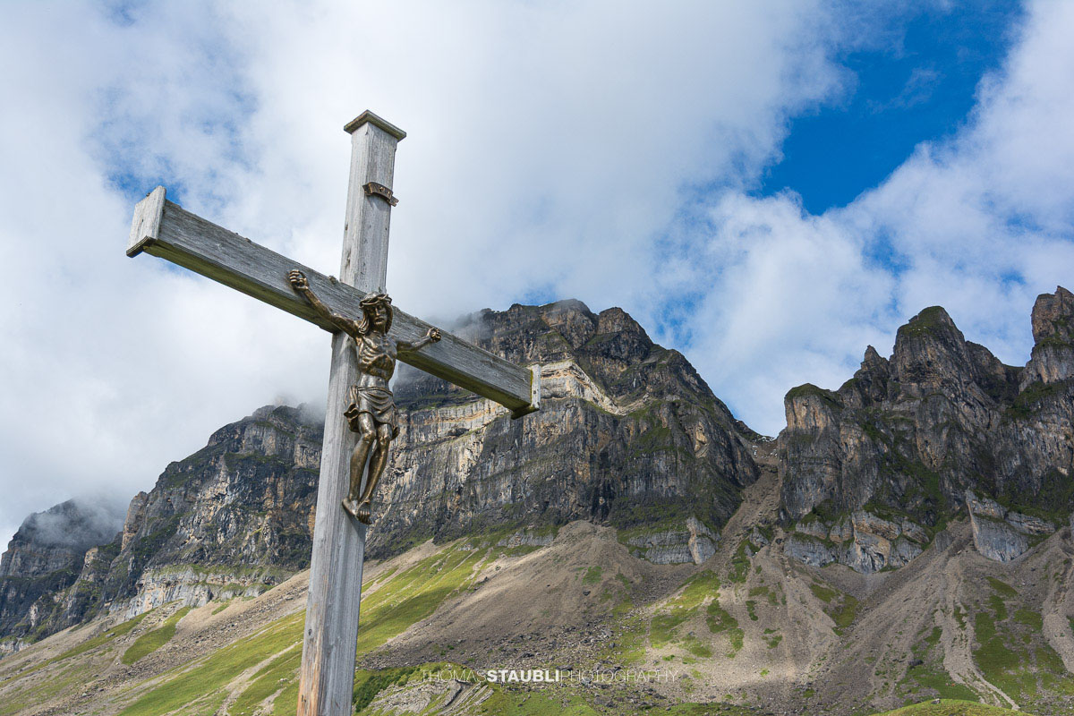 Bergkreuz auf der Seenalp vor der imposanten Felslandschaft im Kanton Uri.