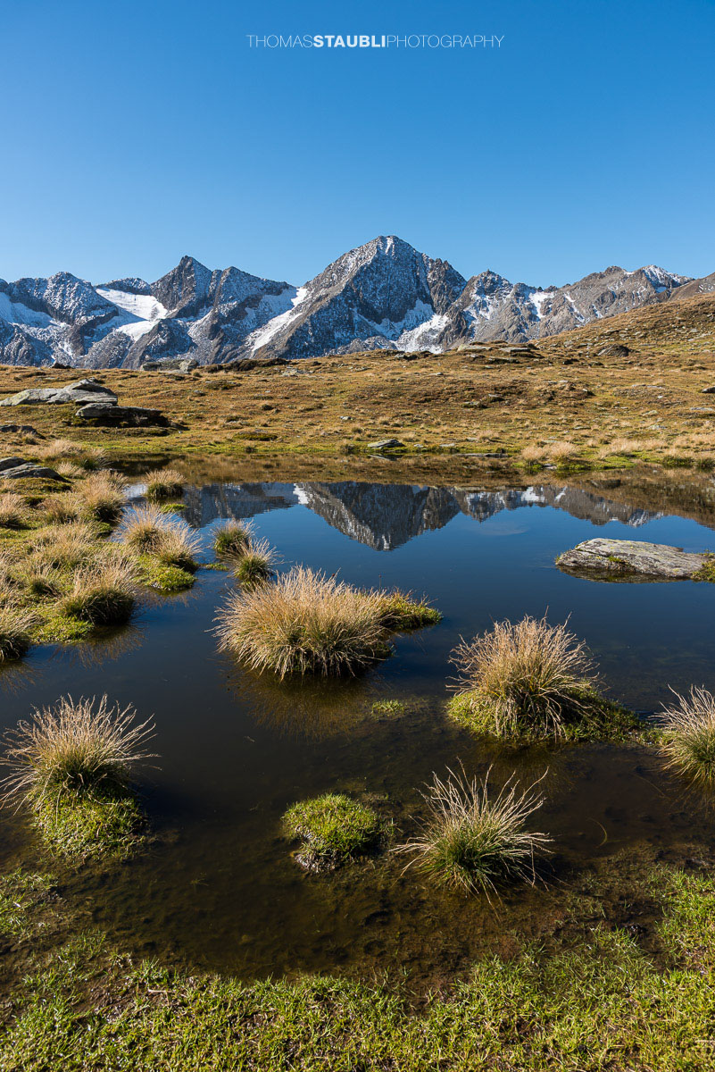 Kleines Seelein unter den Stotzigen Firsten mit Blick zu den Muttenhörnern und spiegelnden Berggipfeln.