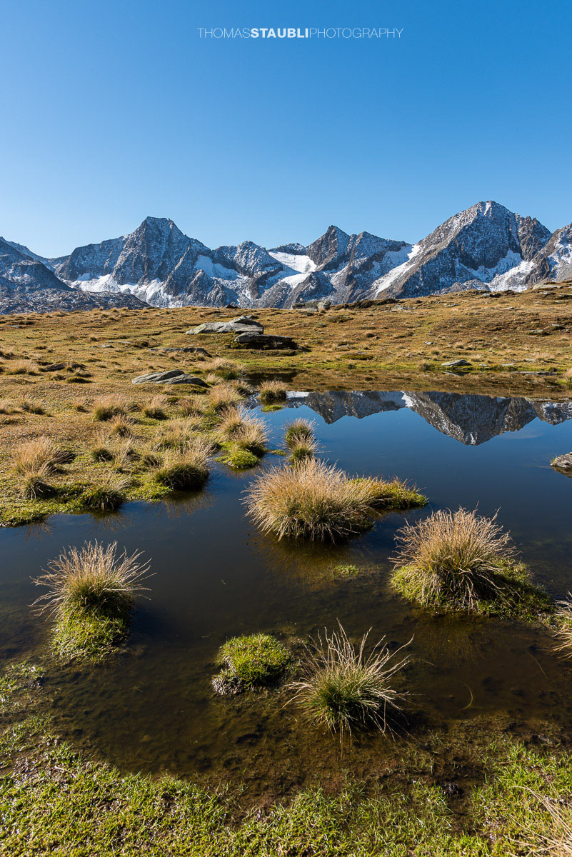 Kleines Seelein unter den Stotzigen Firsten mit Blick zu den Muttenhörnern und spiegelnden Berggipfeln.