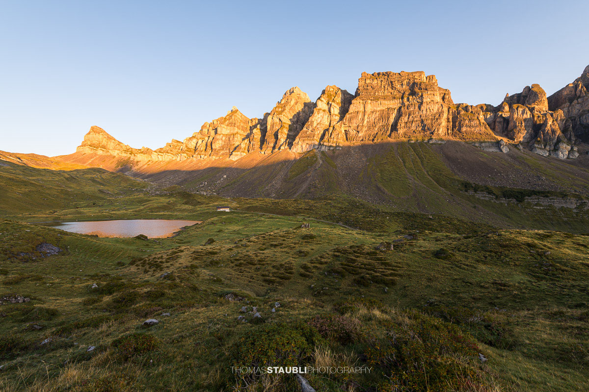Blick über die herbstliche Seenalp zum Chaiserstock, dessen Felswände von der Morgensonne warm beleuchtet werden.