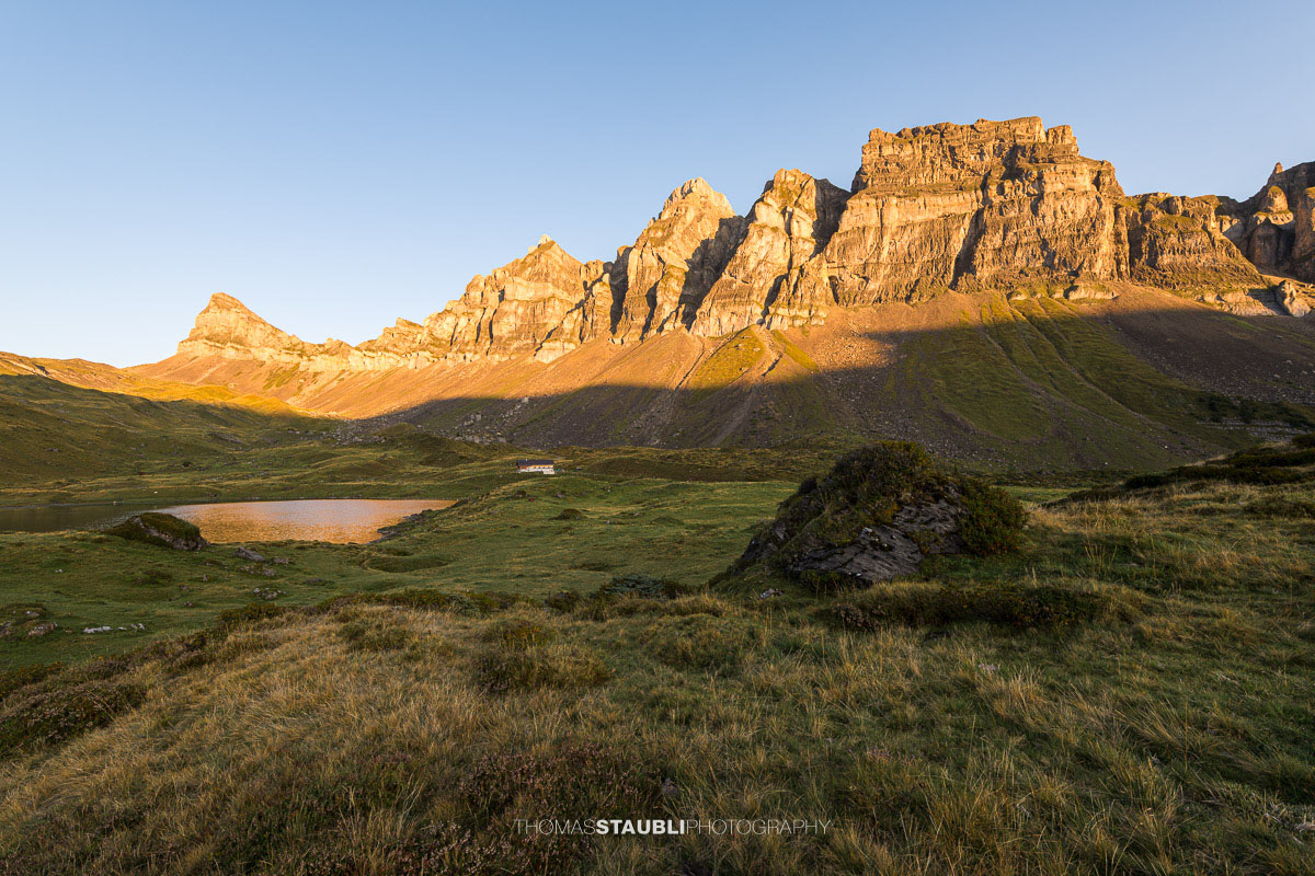 Blick über die herbstliche Seenalp zum Chaiserstock, dessen Felswände von der Morgensonne warm beleuchtet werden.