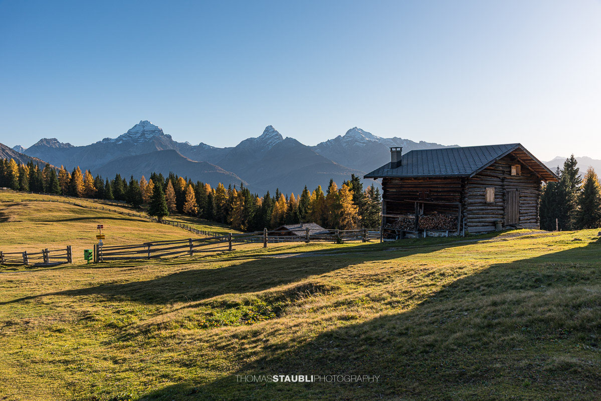 Wiesner Alp mit traditioneller Alphütte und herbstlichen Wiesen, im Hintergrund Piz Ela, Corn da Tinizong und Piz Mitgel.
