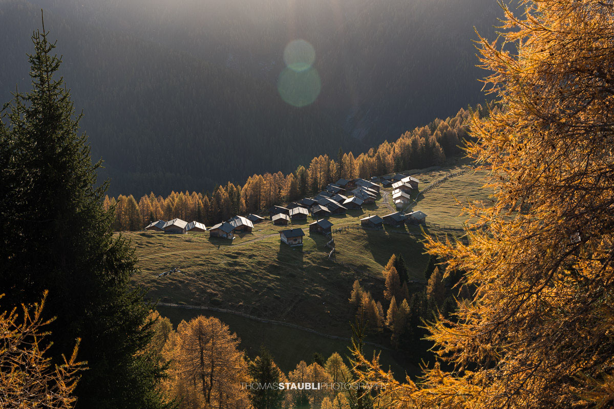 die ersten herbstlichen Sonnenstrahlen erreichen die Wiesner Alp mit den traditionellen Alphütten.