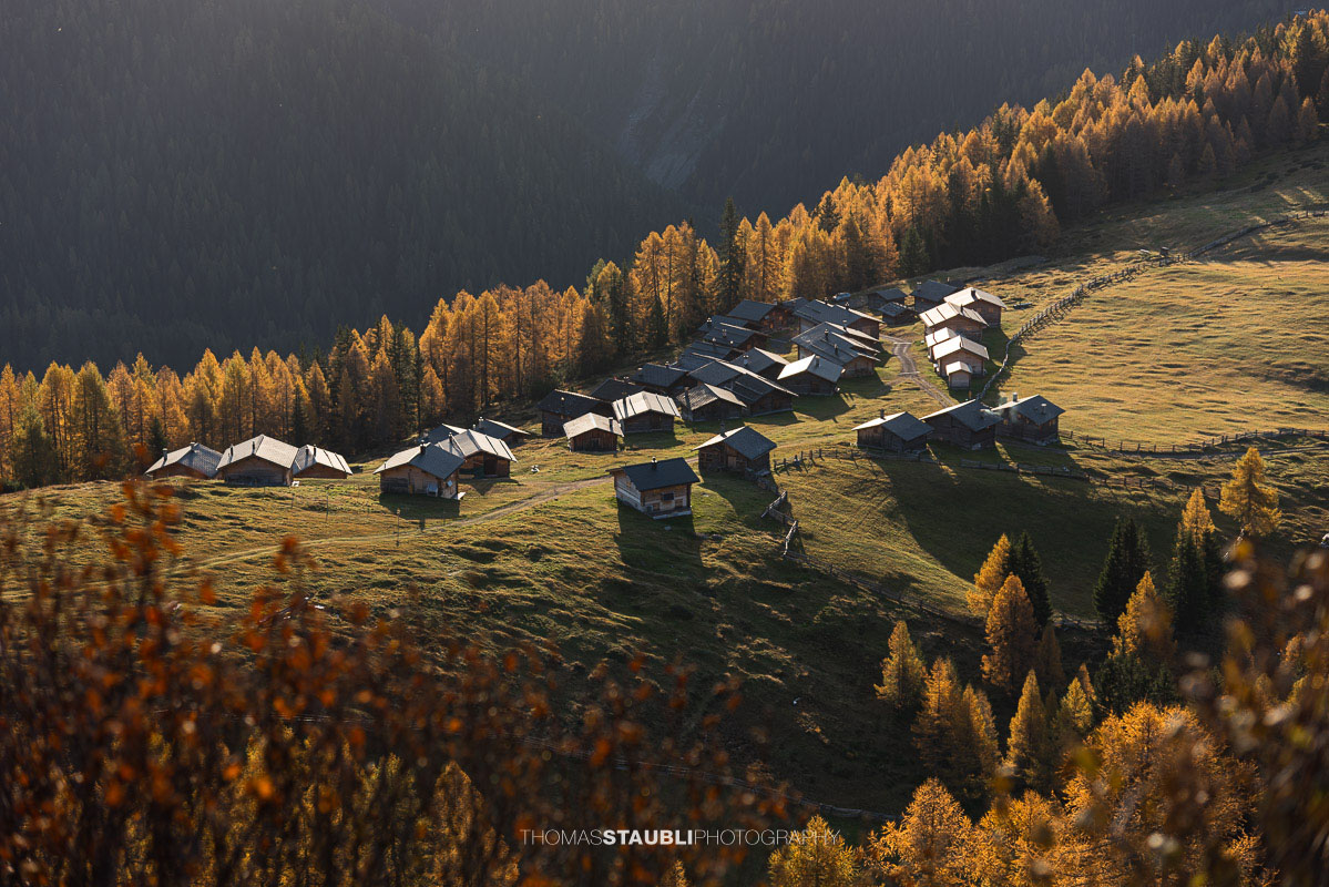 die ersten herbstlichen Sonnenstrahlen erreichen die Wiesner Alp mit den traditionellen Alphütten.